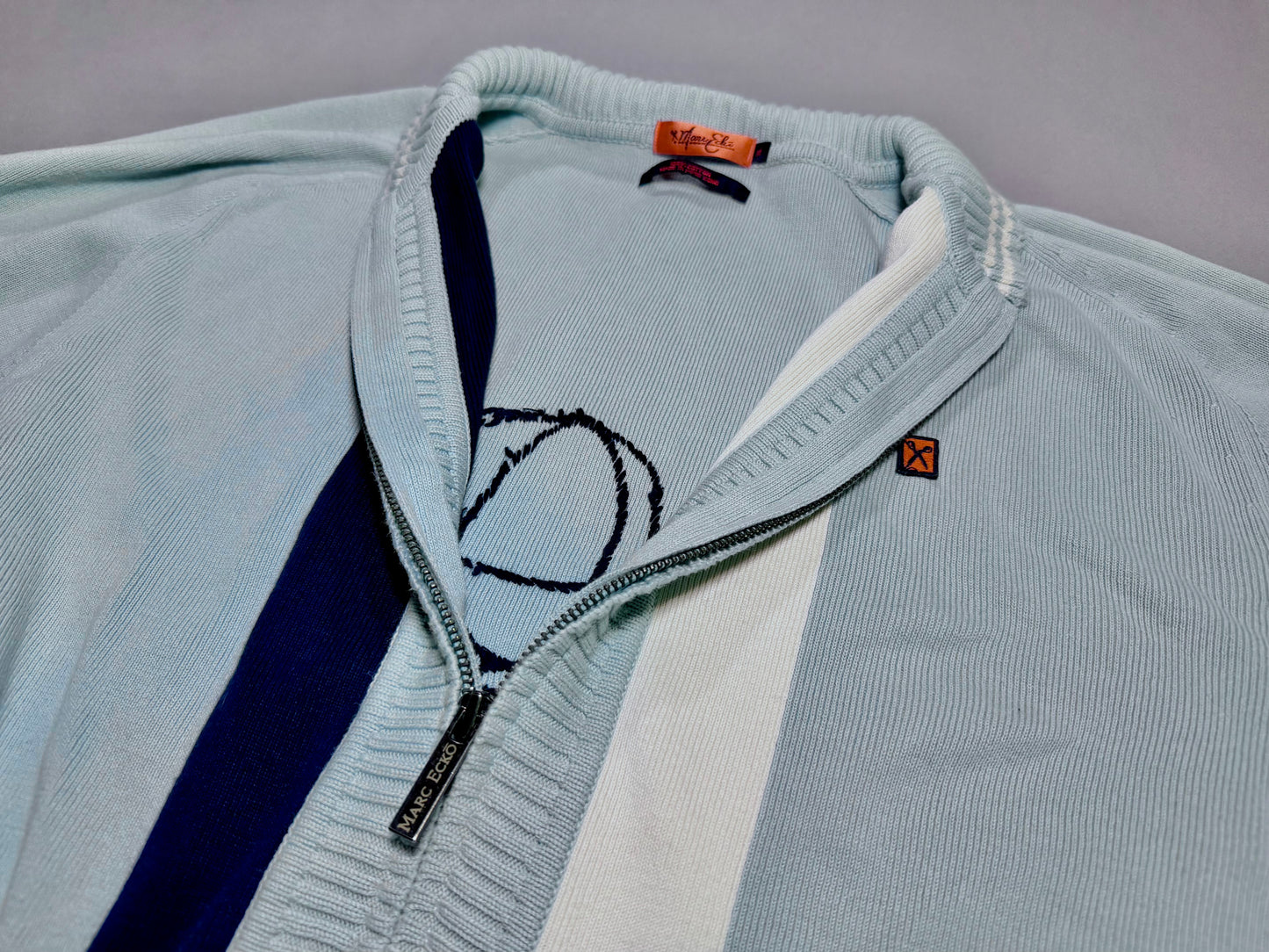 Close-up of the Marc Ecko cardigan front showing zip collar, stripe detail, and embroidered logo.
