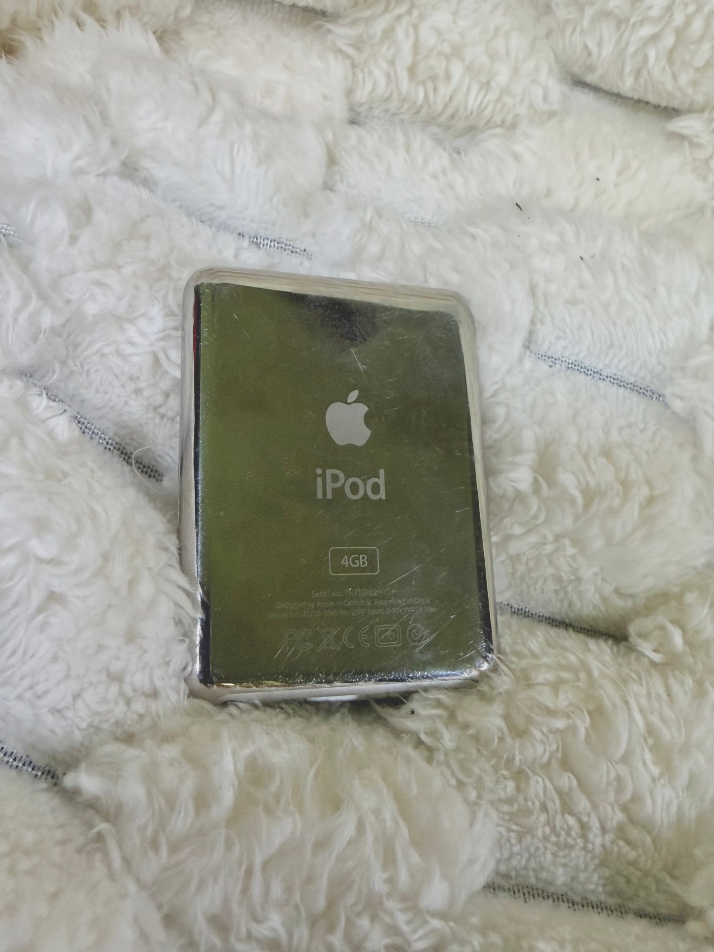 Back of silver Apple iPod nano 3rd generation showing polished metal casing, Apple logo, and 4GB storage marking.