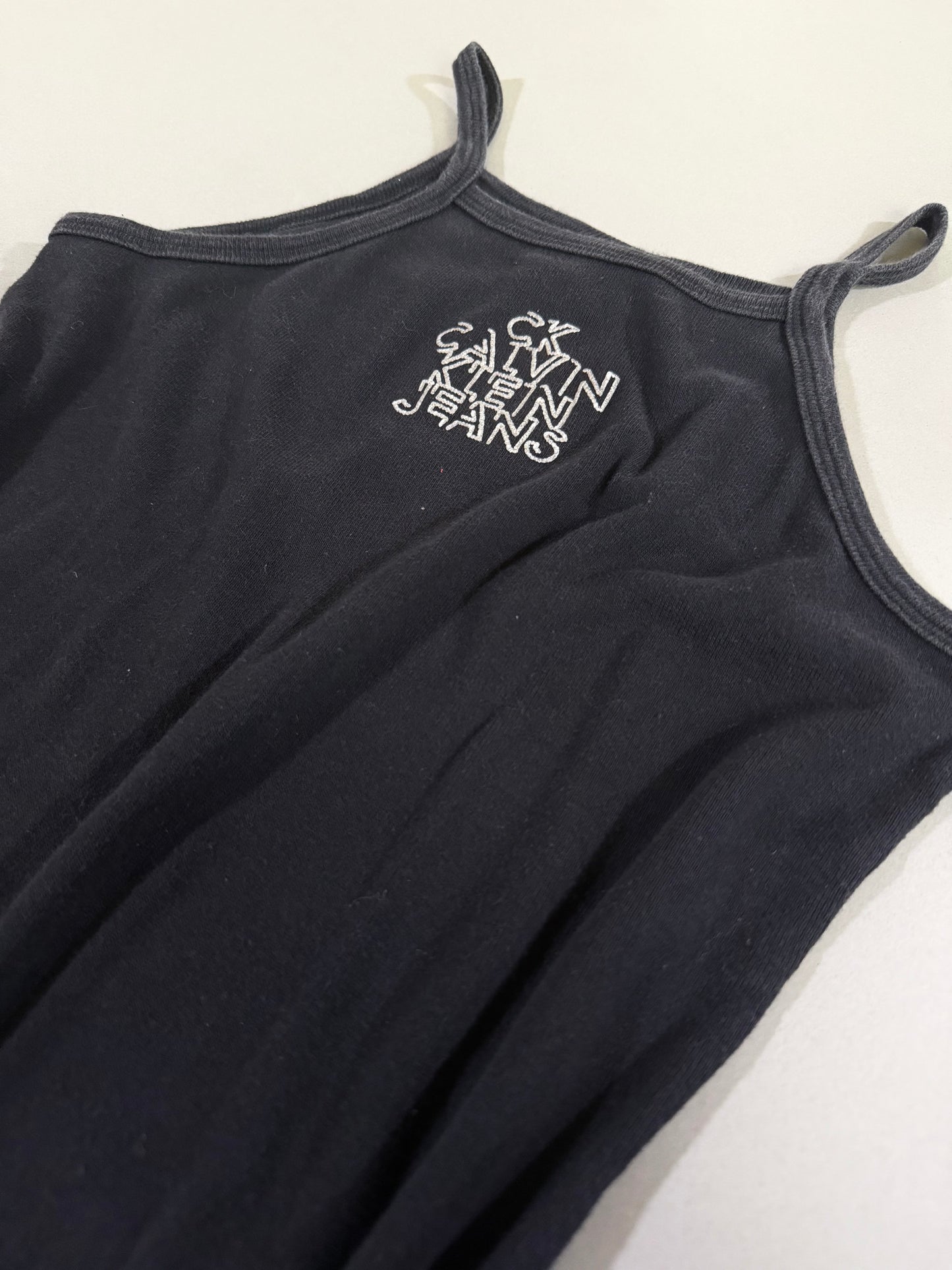 Close-up of printed Calvin Klein Jeans stacked logo on black dress neckline.
