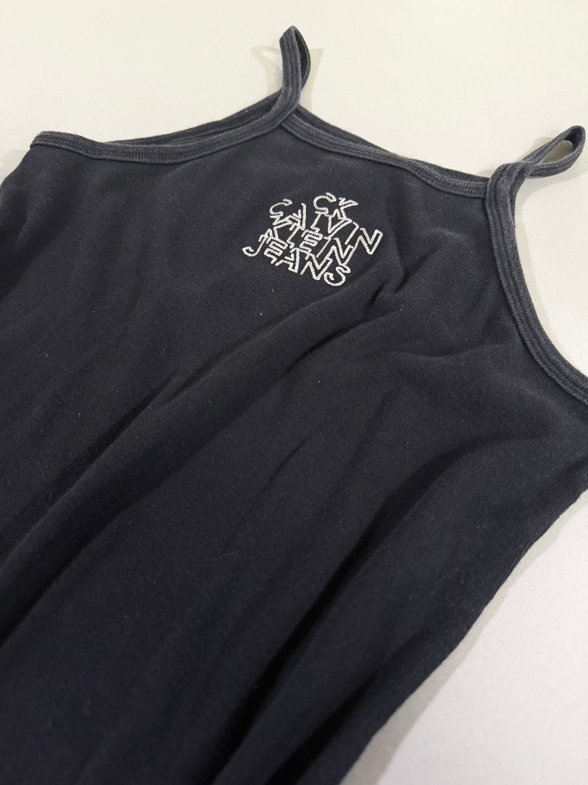 Close-up of printed Calvin Klein Jeans stacked logo on black dress neckline.