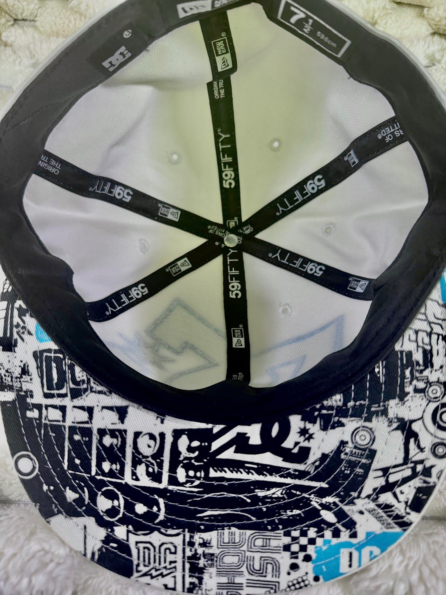 Interior view of vintage DC Shoes New Era 59FIFTY cap showing branded interior taping and black, white and blue graphic underside of brim.