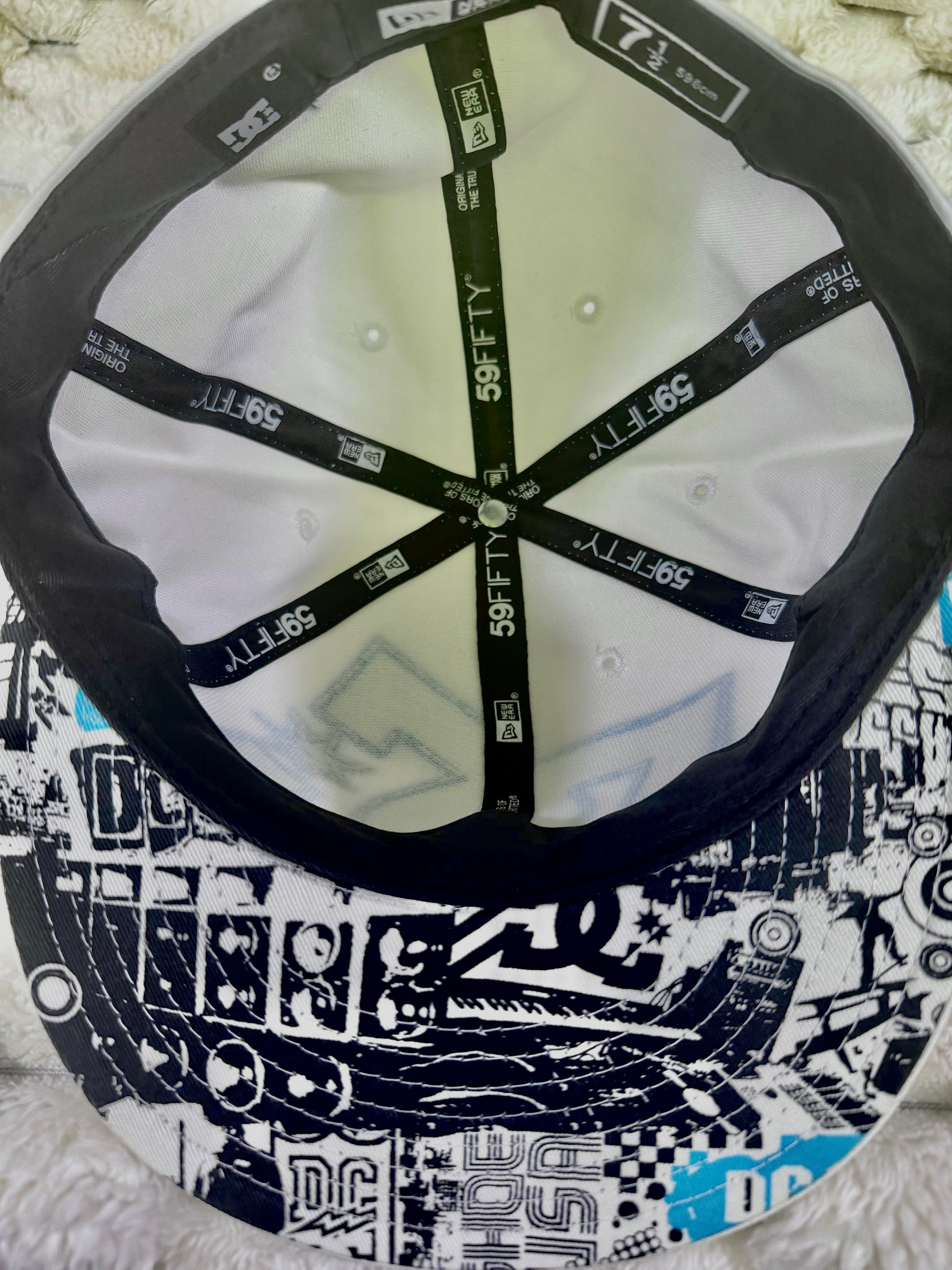 Interior view of vintage DC Shoes New Era 59FIFTY cap showing branded interior taping and black, white and blue graphic underside of brim.