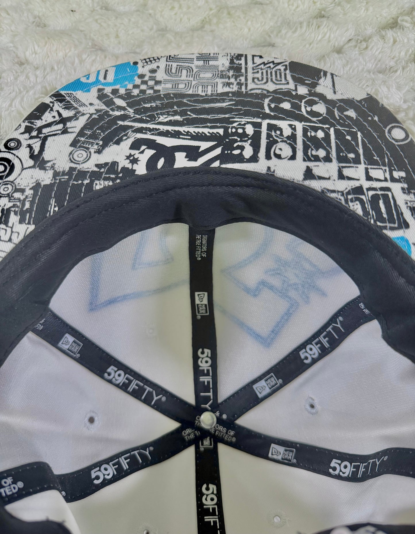 Interior view of vintage DC Shoes New Era 59FIFTY cap showing branded interior taping and black, white and blue graphic underside of brim.