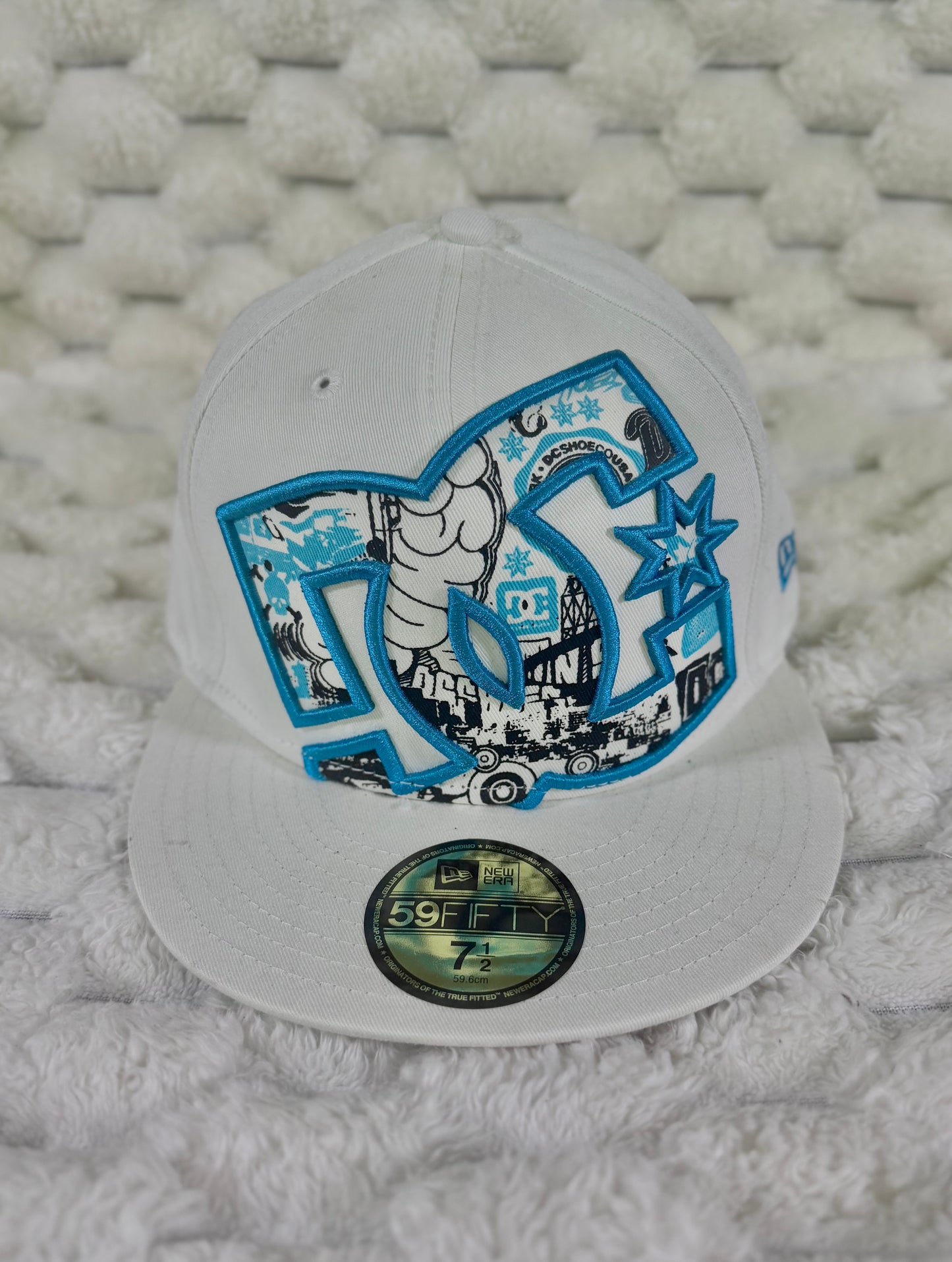 Vintage DC Shoes New Era 59FIFTY white fitted cap with oversized blue embroidered DC logo and black, white and blue skate graphics.