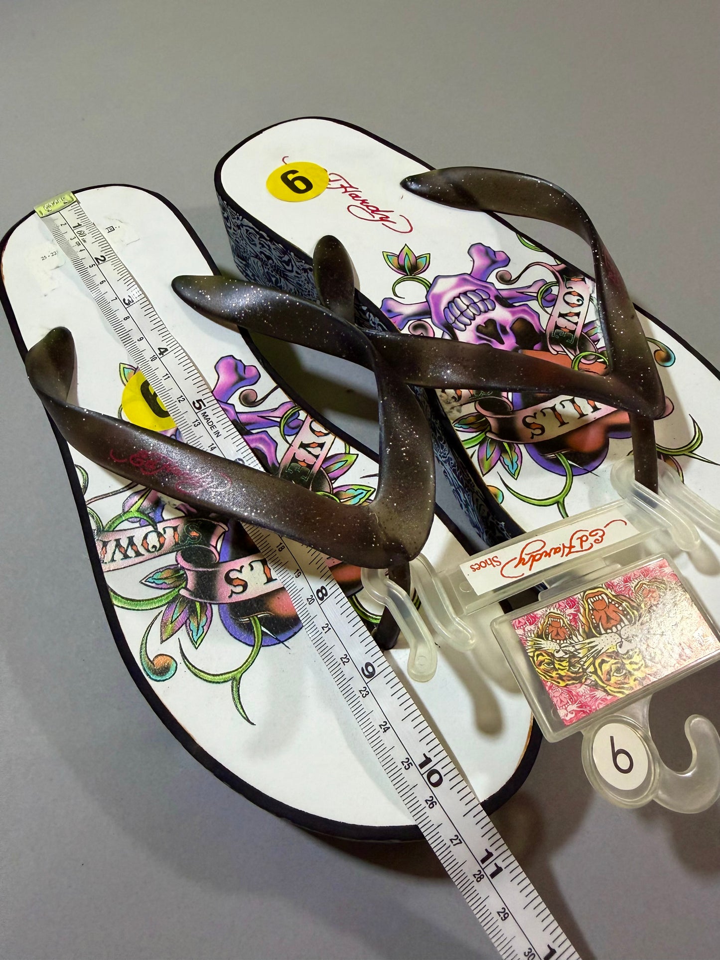 Ed Hardy skull-and-rose platform flip-flops with measuring tape showing an approximately 10.5 inch footbed, women’s size 9.