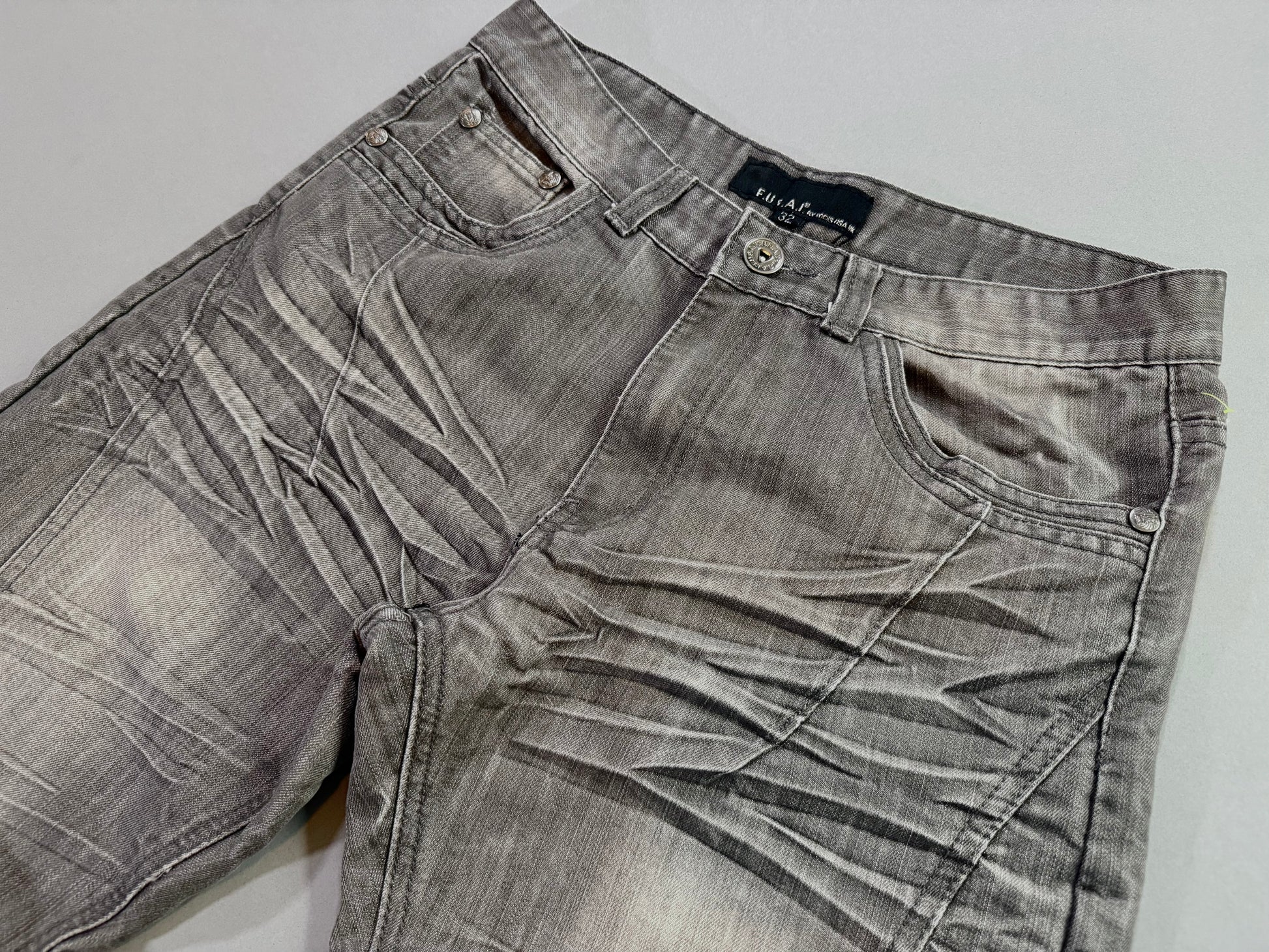 Close-up of the waistband, front pockets, and whiskered fade detailing on F.U.S.A.I. jeans.
