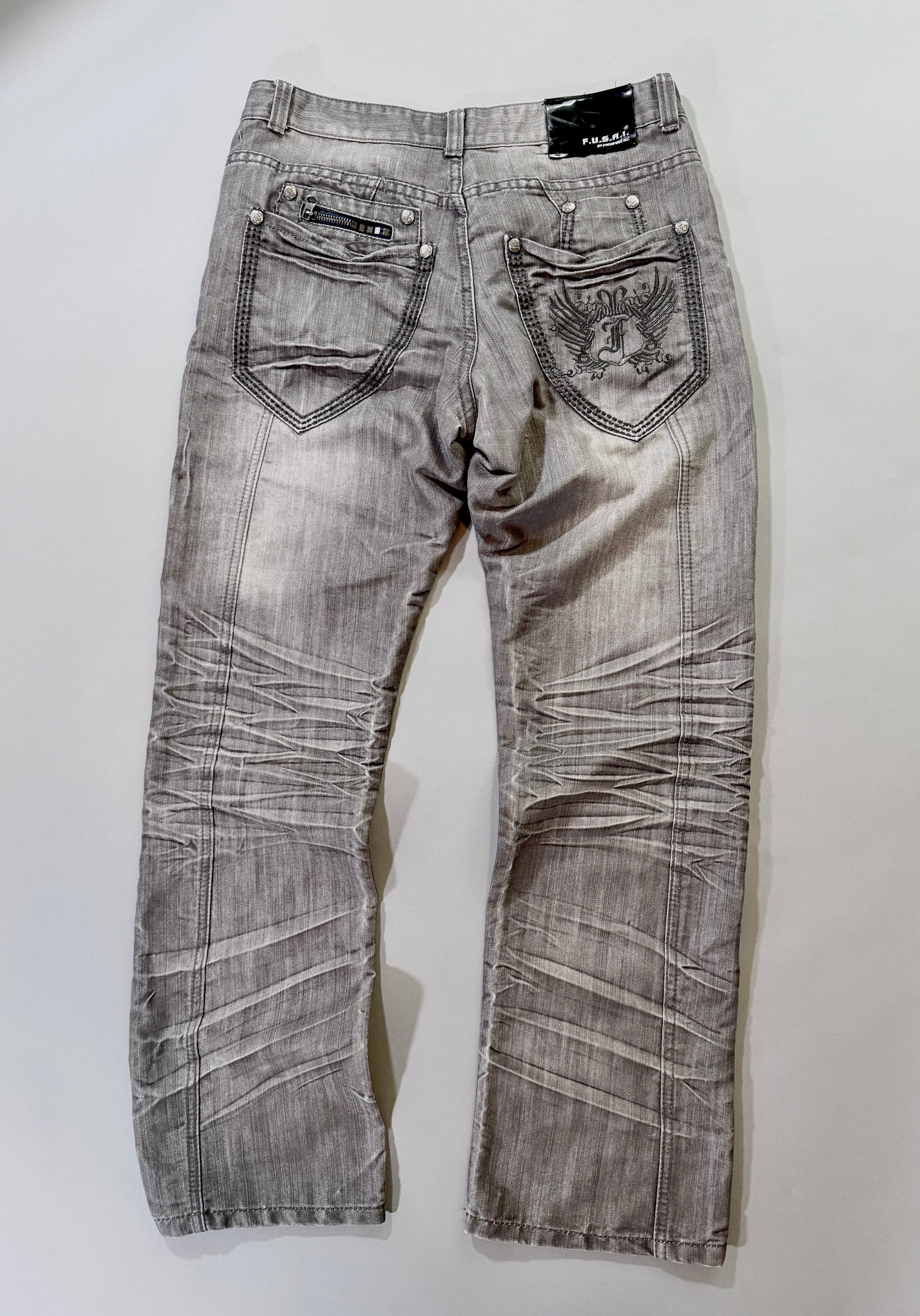 Back view of F.U.S.A.I. grey wash jeans featuring embroidered crest pocket, decorative zipper, and logo patch.