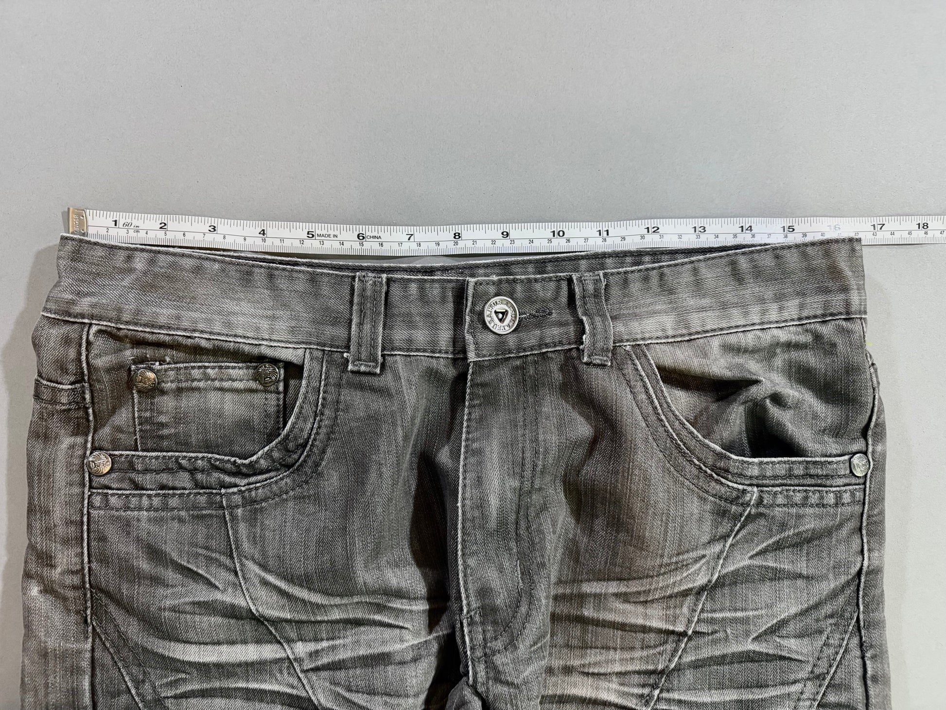 Waist measurement of the F.U.S.A.I. men’s grey wash jeans shown laid flat.