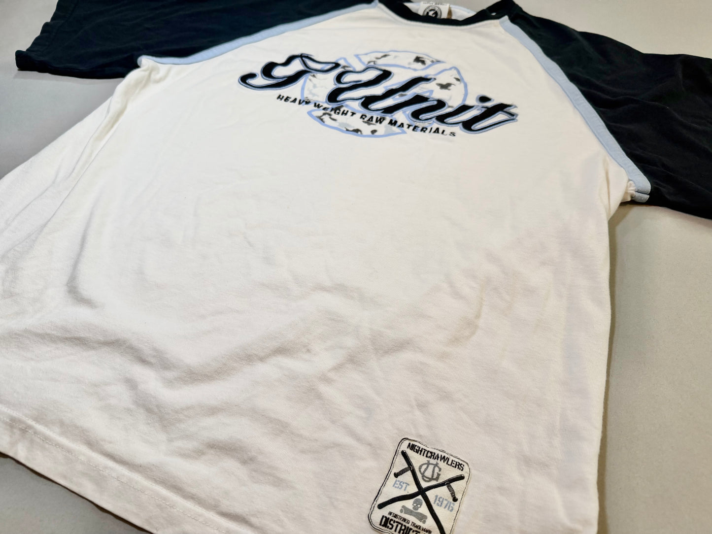 Lower front detail showing the Nightcrawlers District Six woven hem patch.
