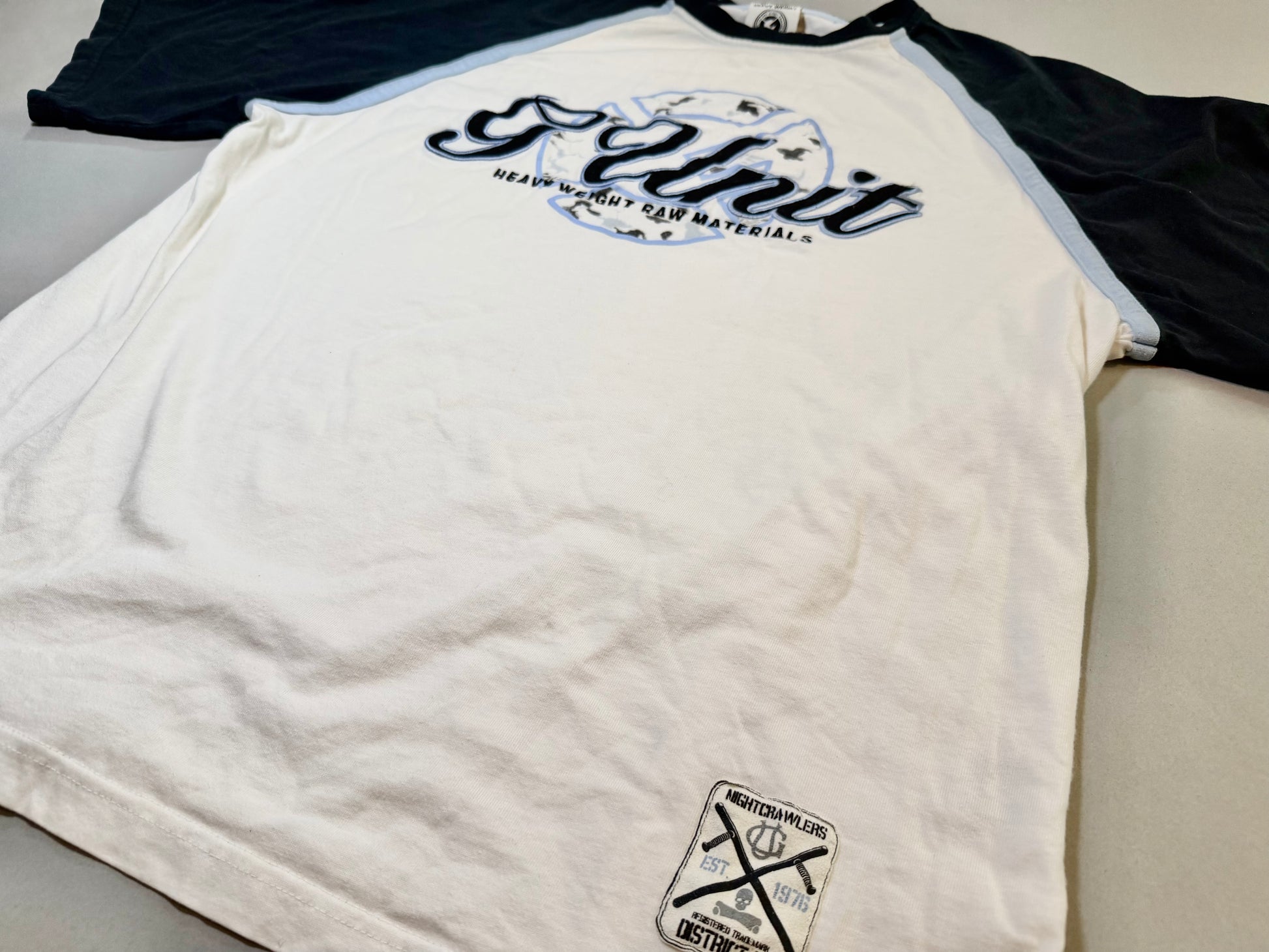 Lower front detail showing the Nightcrawlers District Six woven hem patch.