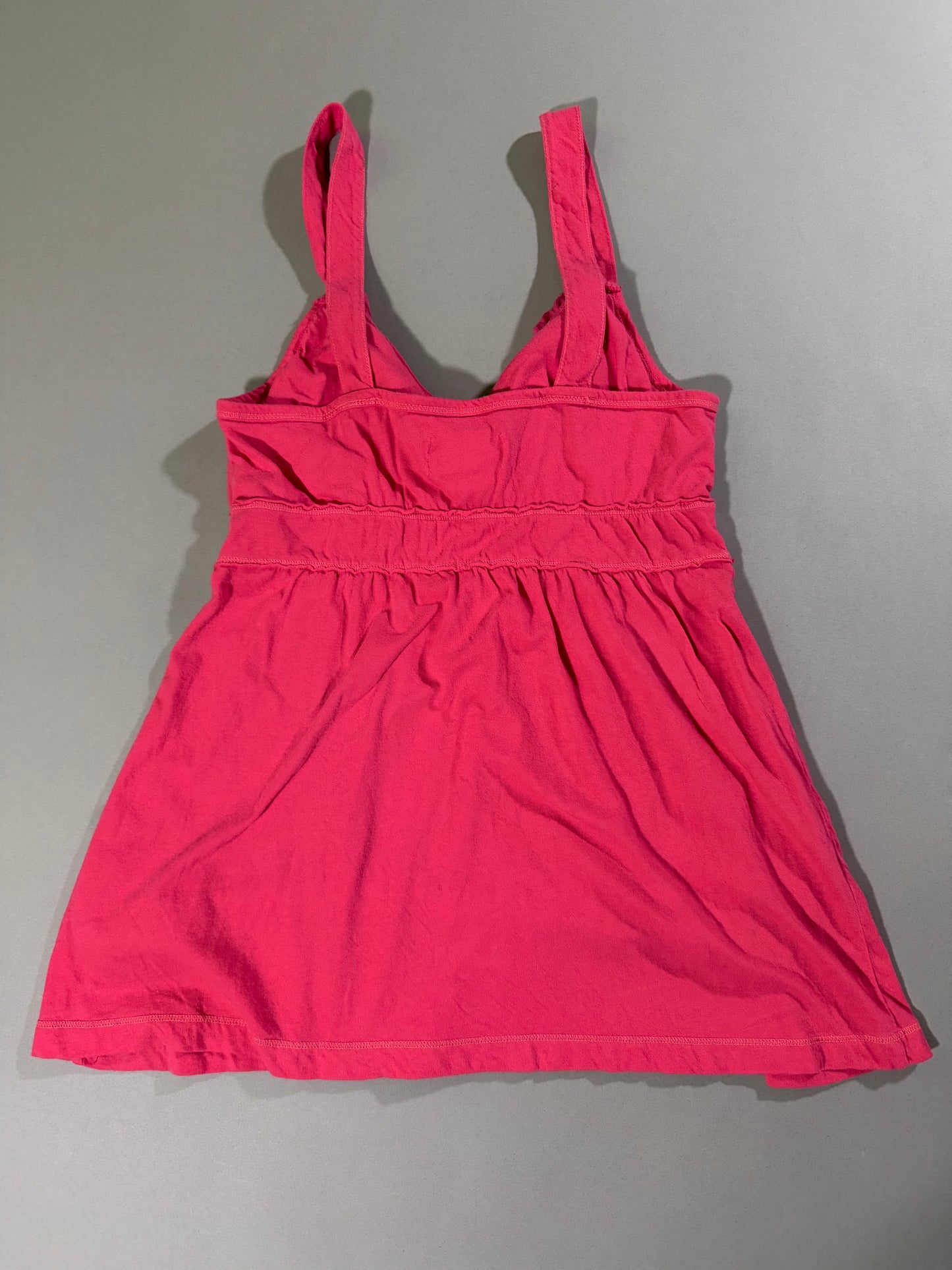 Back view of the vintage Hollister coral pink babydoll tank top with wide straps, gathered empire waist and flared silhouette.