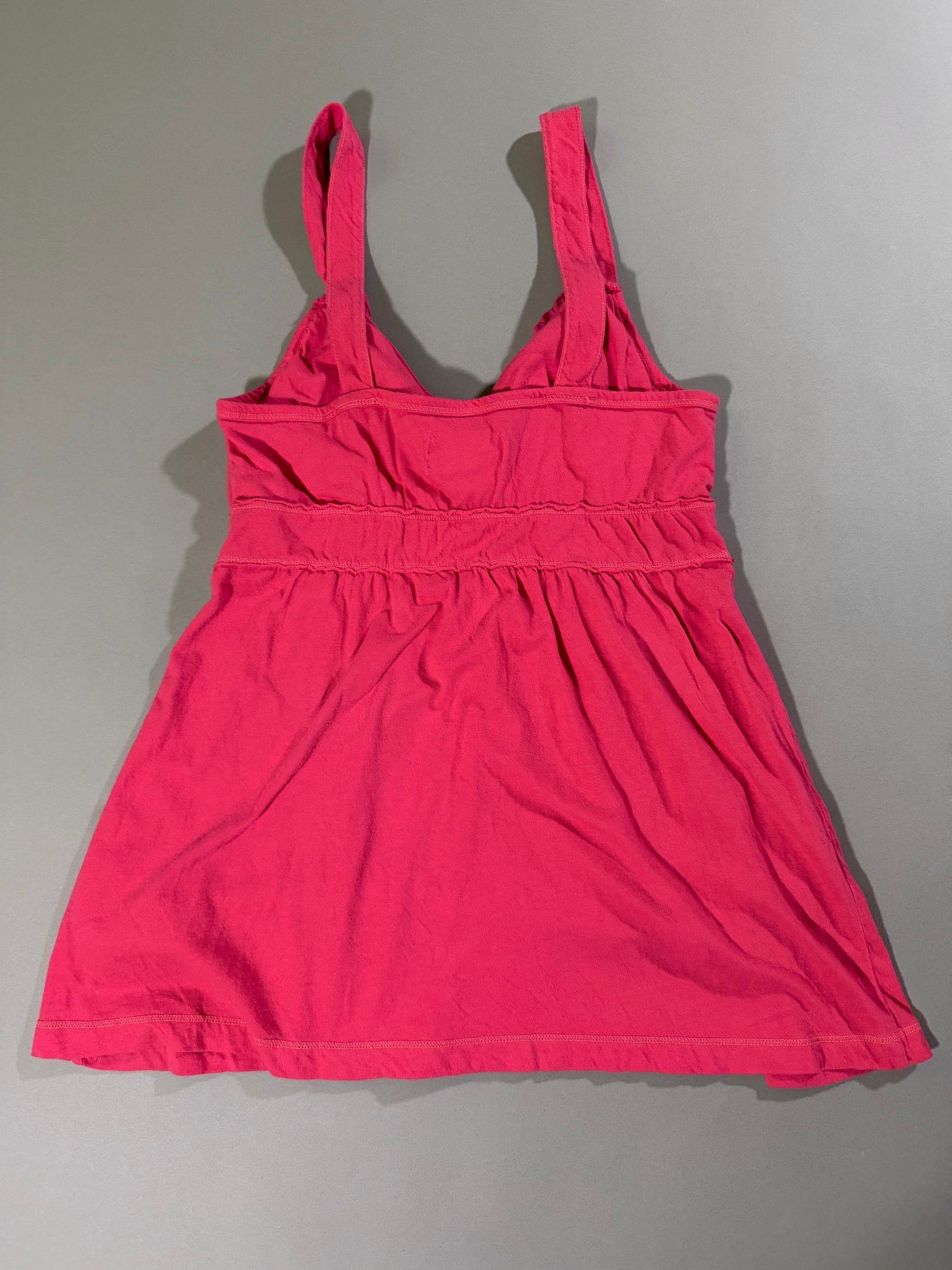 Back view of the vintage Hollister coral pink babydoll tank top with wide straps, gathered empire waist and flared silhouette.