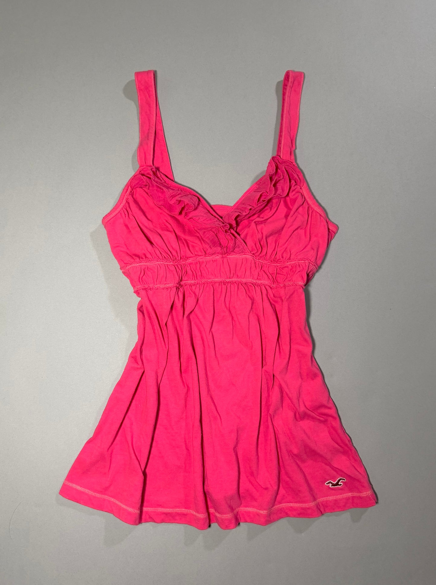 Vintage Hollister coral pink babydoll tank top with ruffled V-neckline, gathered empire waist and embroidered seagull logo at the hem.