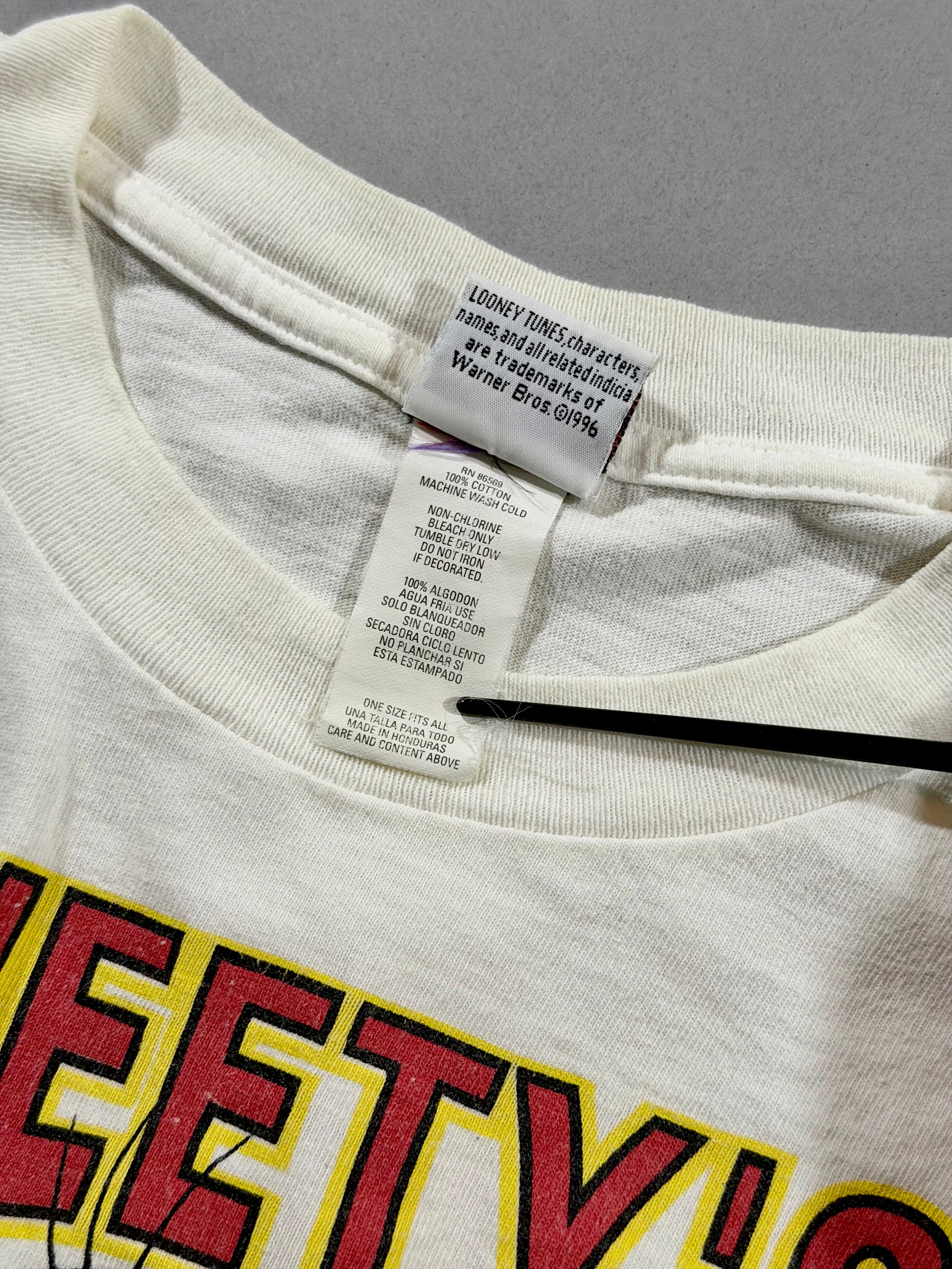 Interior tag showing 1996 Looney Tunes trademark, 100% cotton fabric, Made in Honduras, and One Size Fits All label.