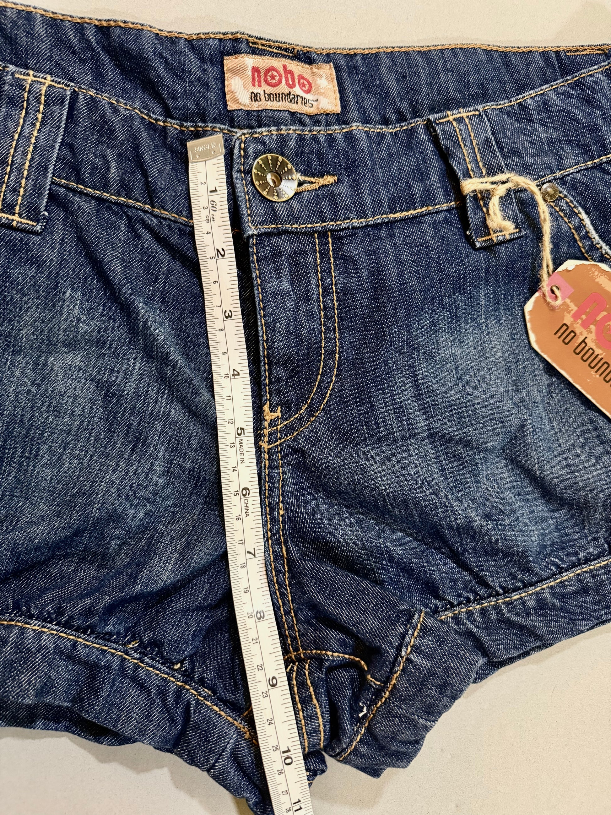 Close-up showing front rise measurement on NWT Nobo denim shorts.