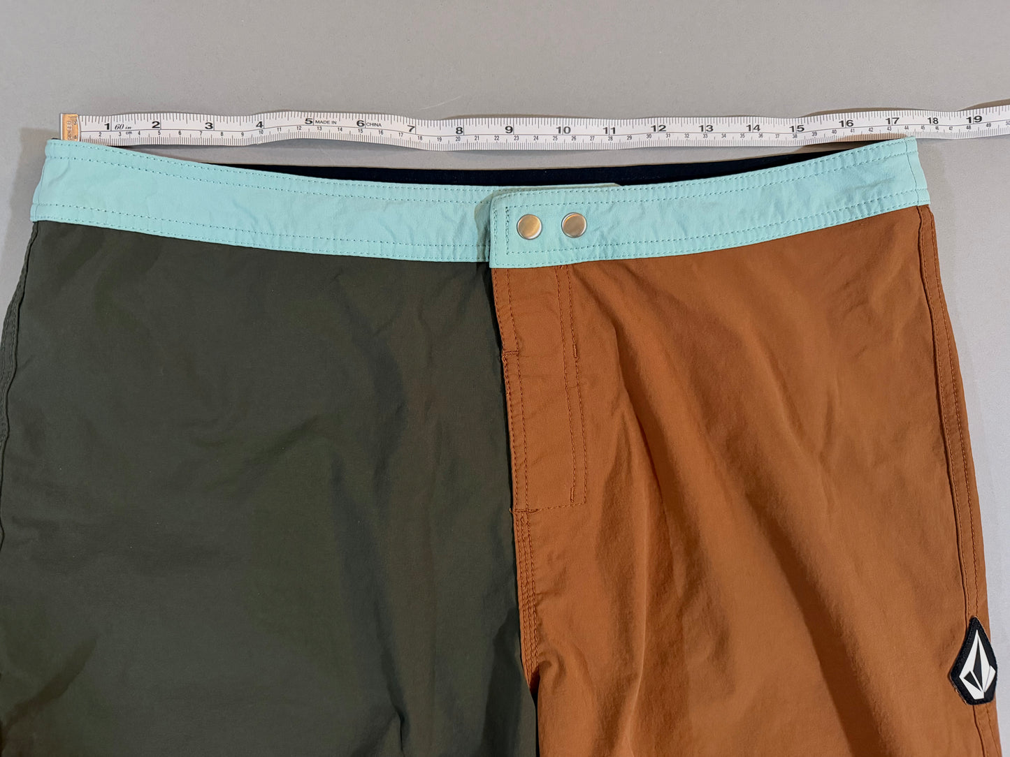 Waistband close-up showing snap closure and color block panels on Volcom boardshorts.