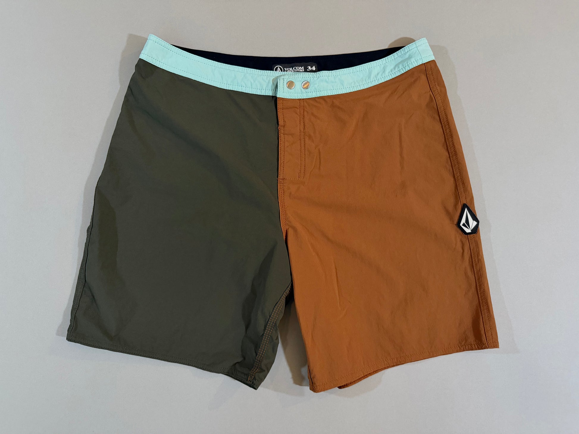 Front view of Volcom color block boardshorts in olive green, rust brown, and aqua, men’s size 34.