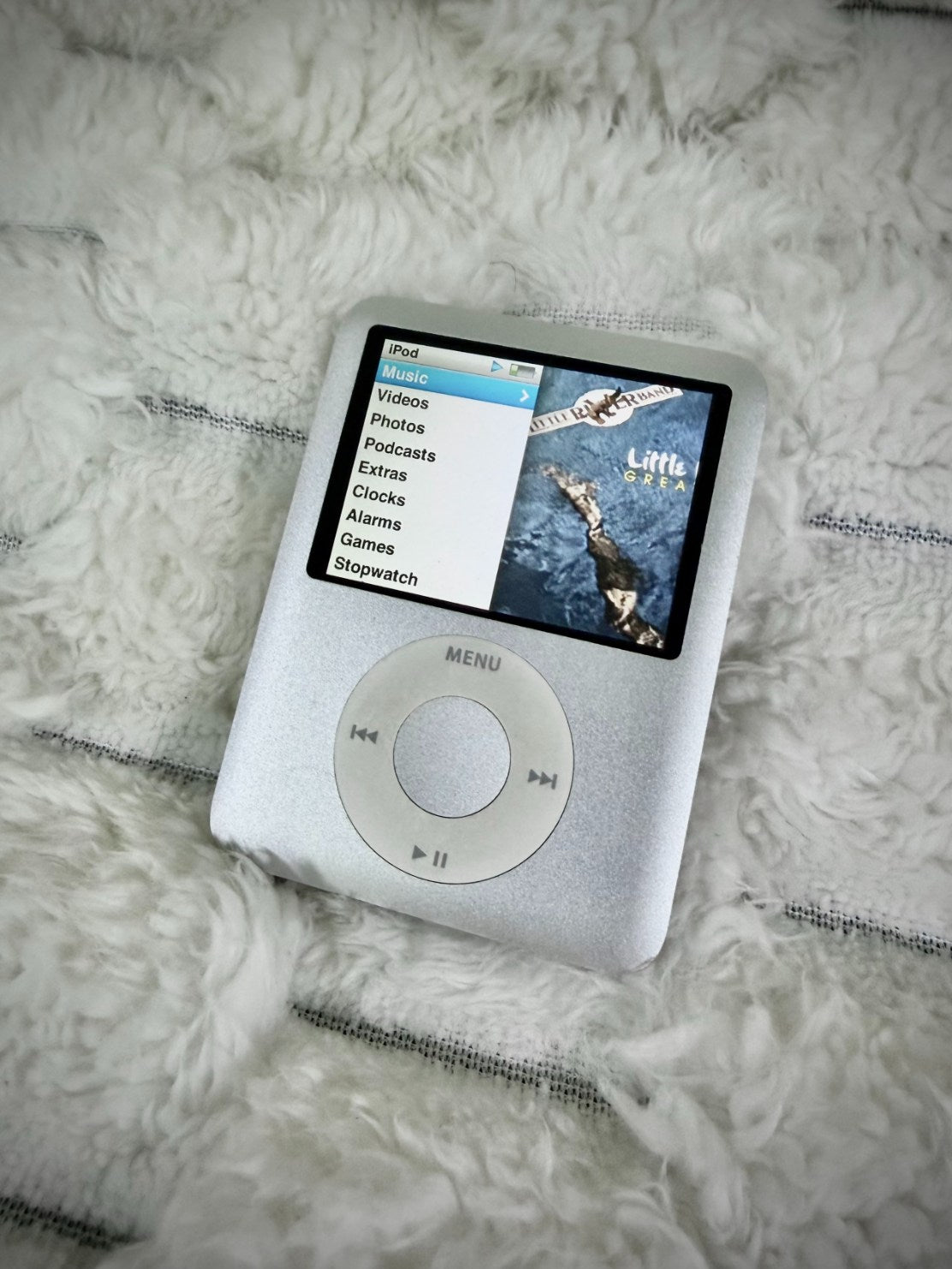 Vintage silver Apple iPod nano 3rd generation with color display showing music menu and Little River Band album artwork.