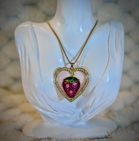 Betsey Johnson gold-tone necklace displayed on a jewelry bust featuring a rhinestone heart pendant with a sparkling pink crystal strawberry.