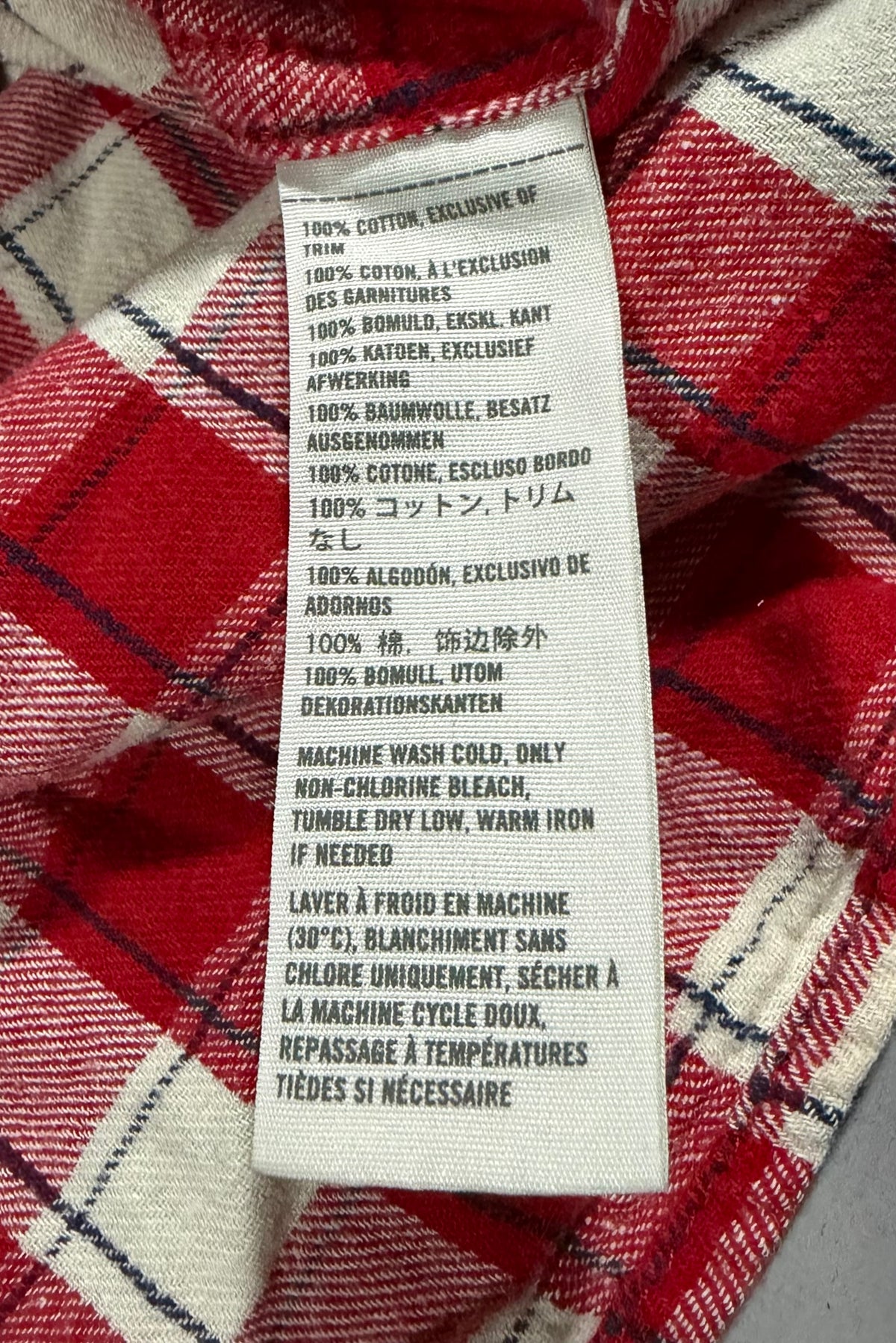 Close up of side seam care tag showing 100% cotton and wash instructions. 