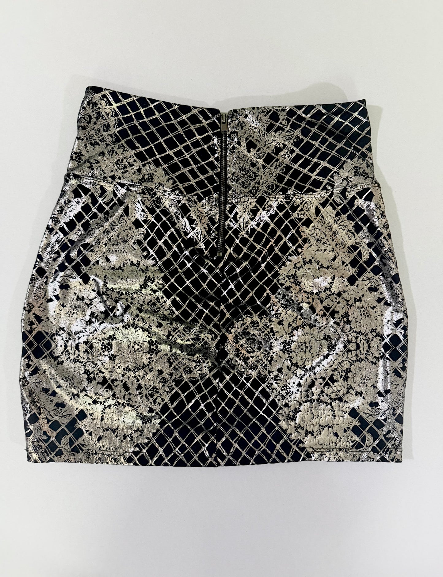 Back view of Bebe black and silver metallic mini skirt with exposed zipper closure.