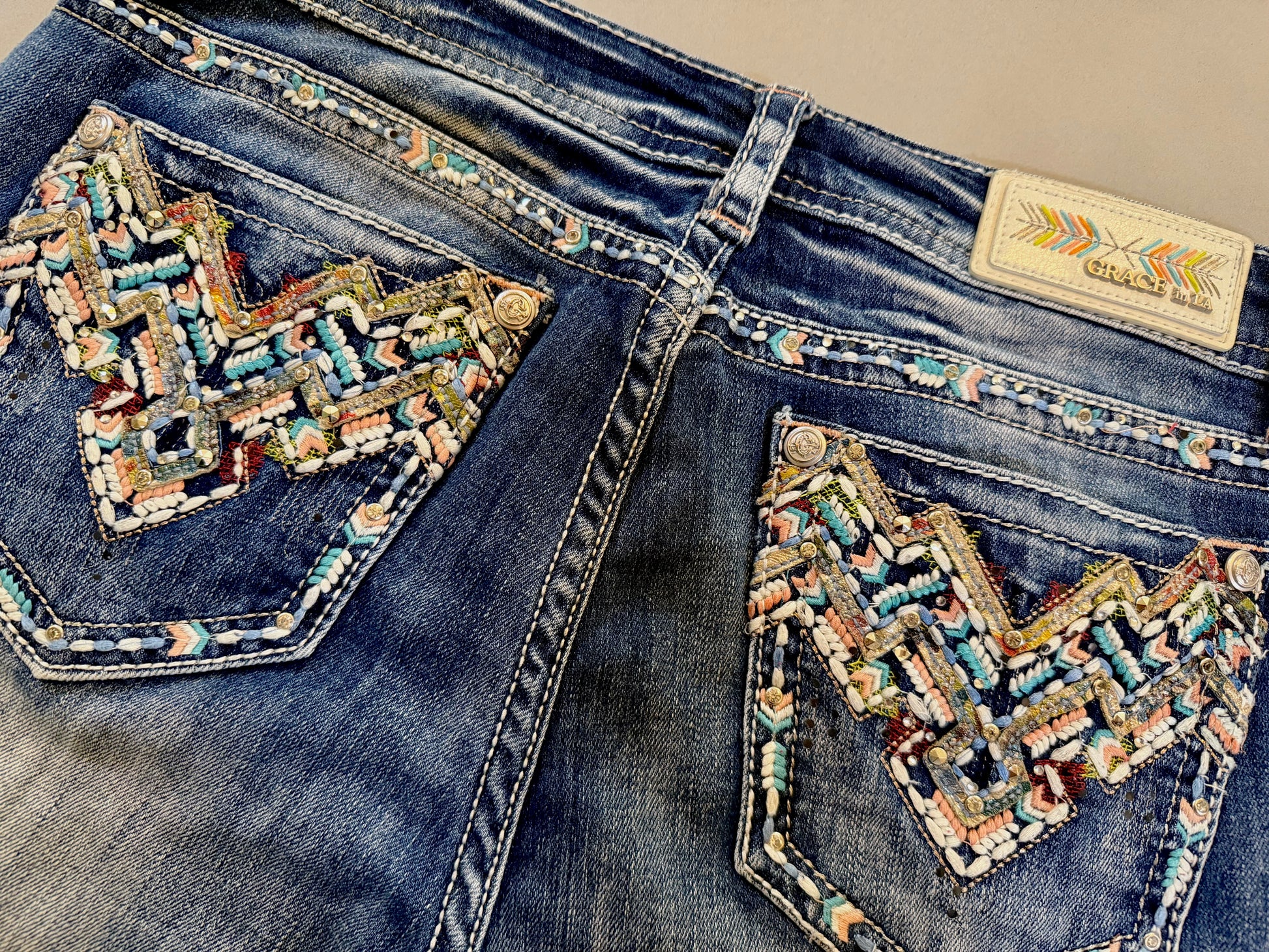 Close up of embroidered and embellished back pockets with rhinestones and pastel boho stitching 