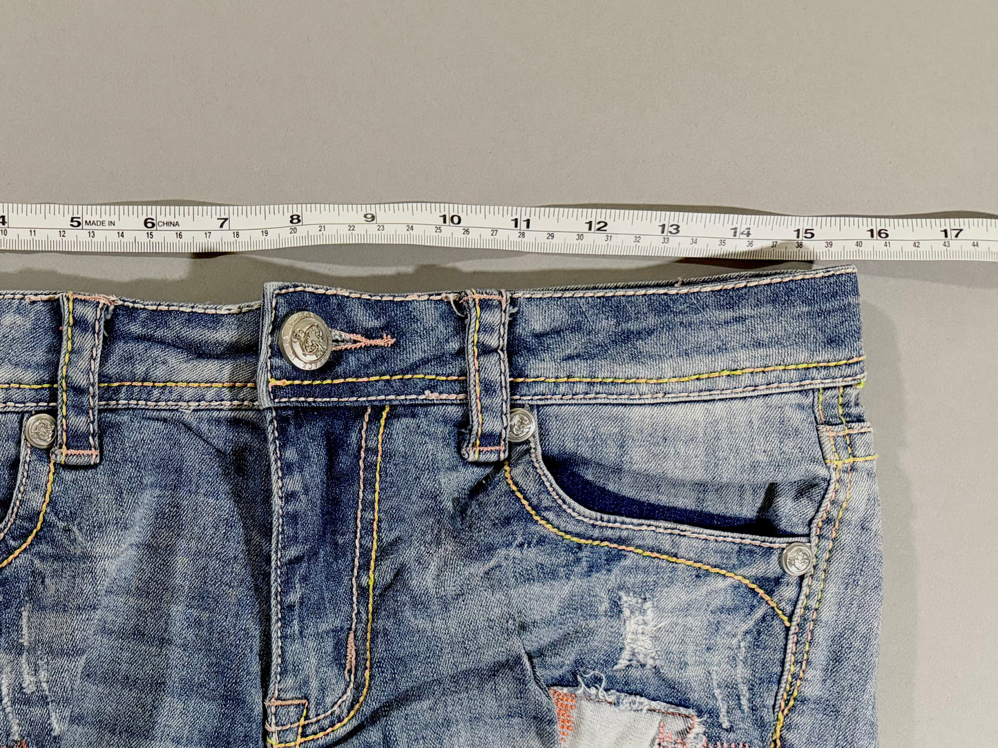 Waist measurement of Grace in LA high rise denim shorts showing approximately 16 inches laid flat.