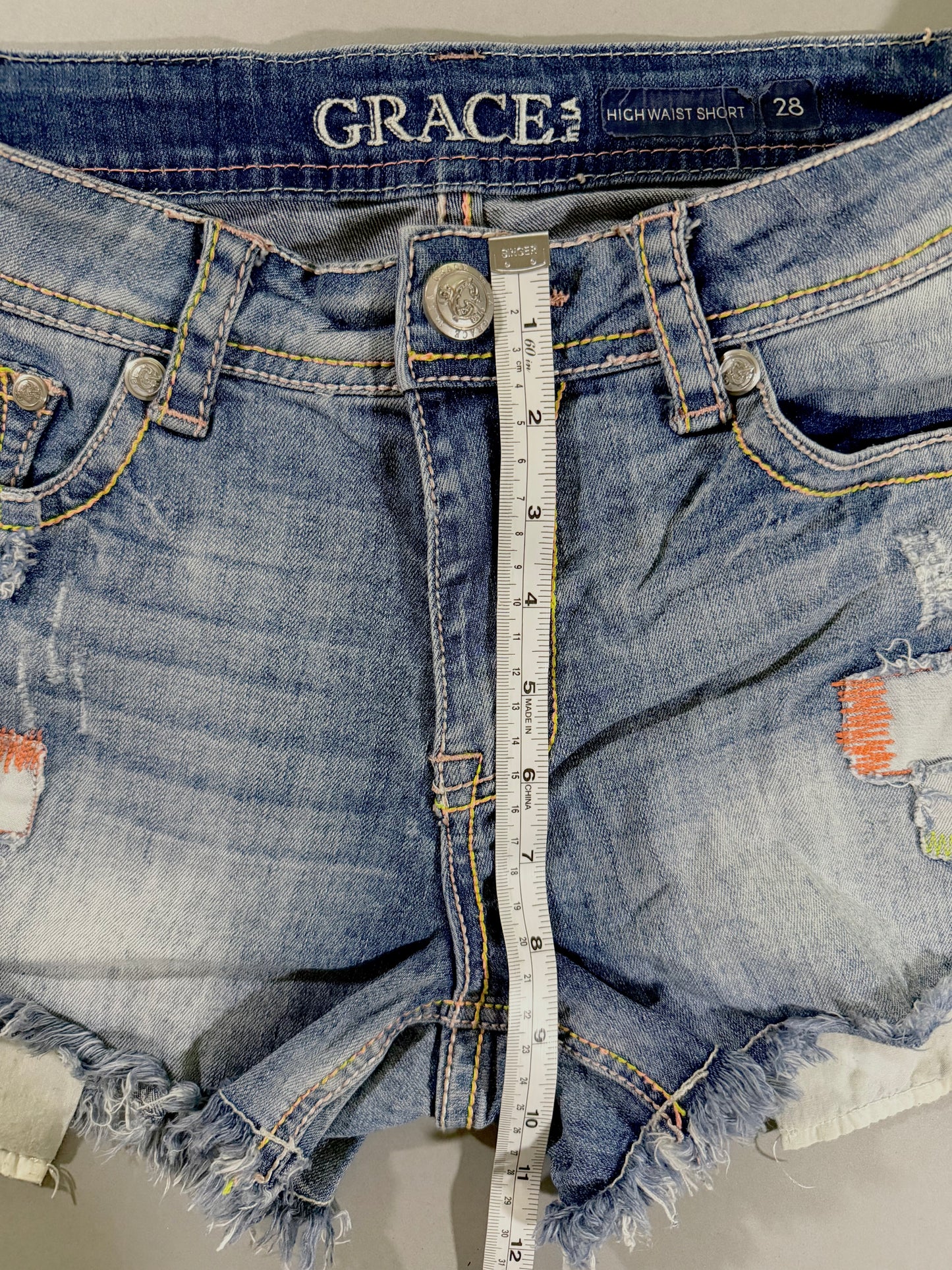 Front rise measurement of Grace in LA high rise denim shorts showing approximately 9 inches from crotch seam to waistband.