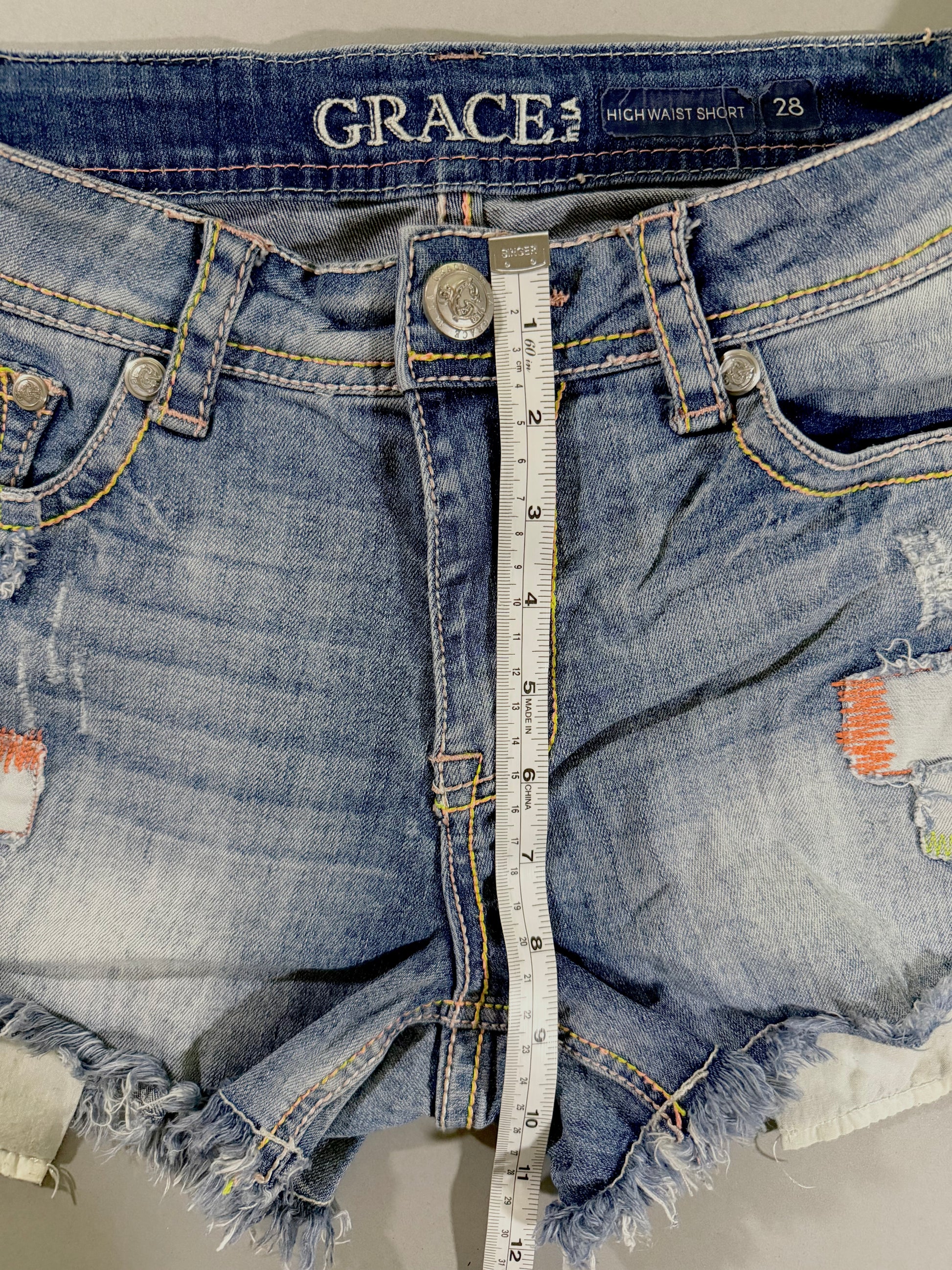 Front rise measurement of Grace in LA high rise denim shorts showing approximately 9 inches from crotch seam to waistband.