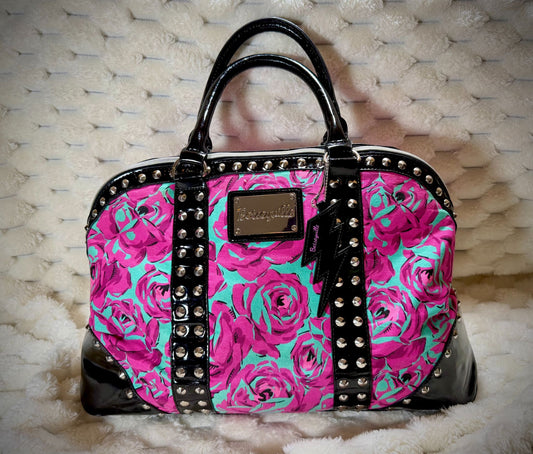 Betseyville by Betsey Johnson floral duffel featuring vibrant pink roses, turquoise background, black patent trim, silver studs, and lightning bolt charm.