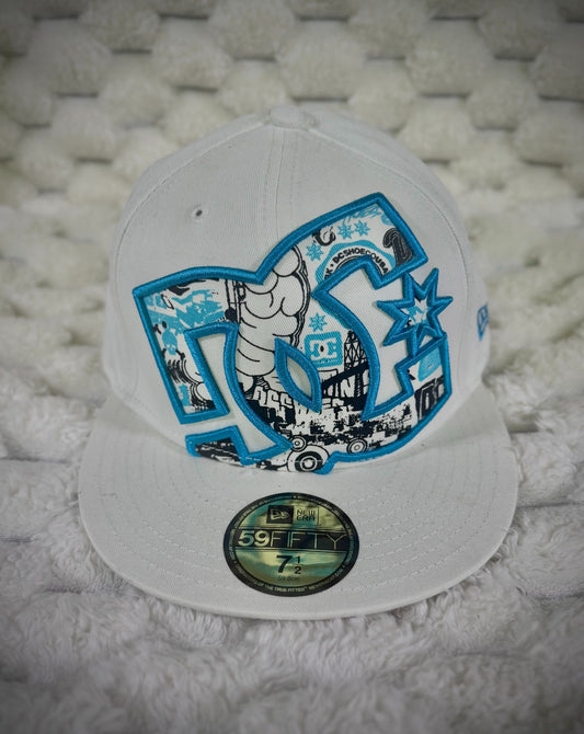 Vintage DC Shoes New Era 59FIFTY white fitted cap with oversized blue embroidered DC logo and black, white and blue skate graphics.