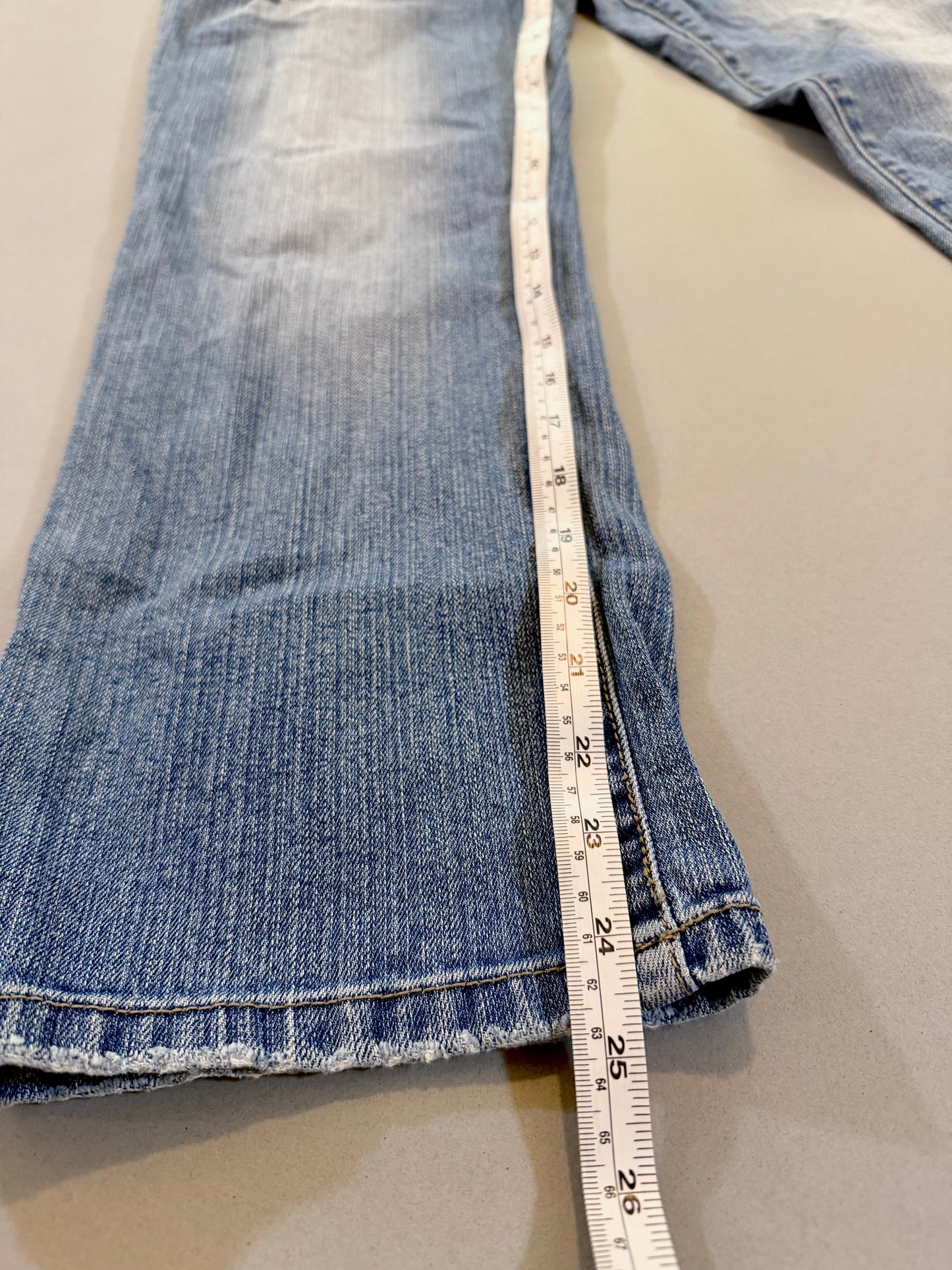 Close up of Delia’s bootcut blue jeans with Measuring tape showing 24.5 inch inseam 