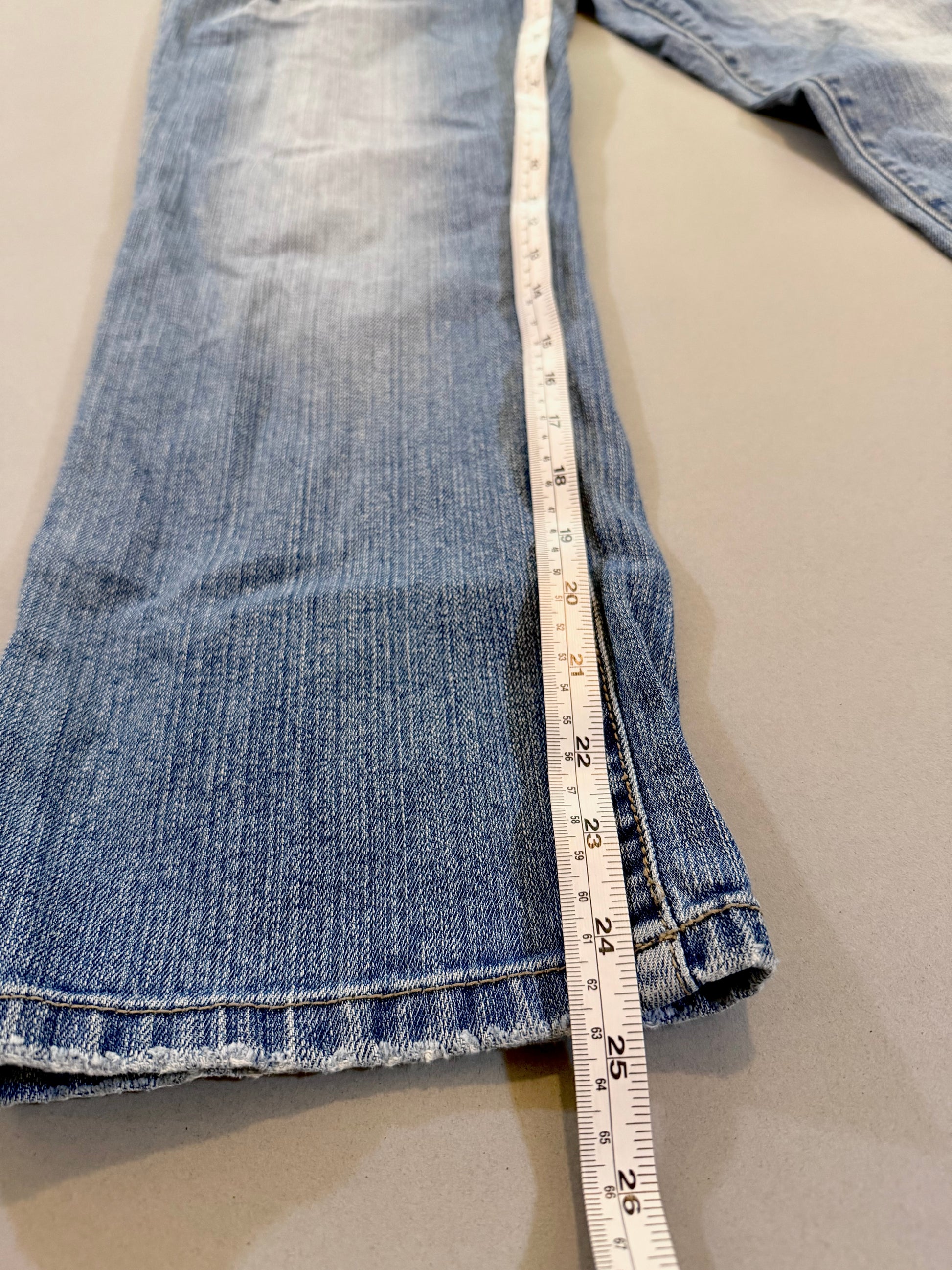 Close up of Delia’s bootcut blue jeans with Measuring tape showing 24.5 inch inseam 