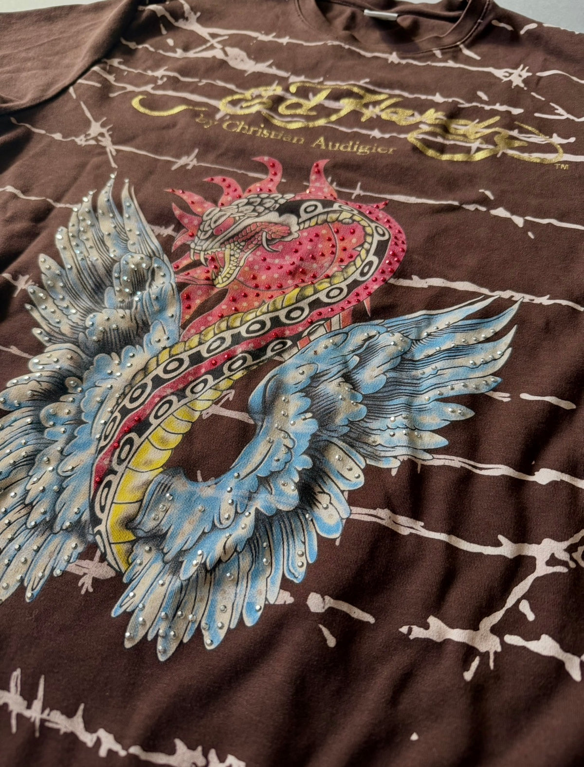 Angled photo of rhinestone-embellished Ed Hardy tattoo-style snake with wings graphic on vintage t-shirt. 