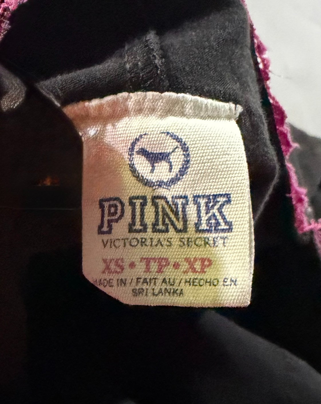Garment tag on waistband of yoga pants showing PINK by Victoria’s Secret.